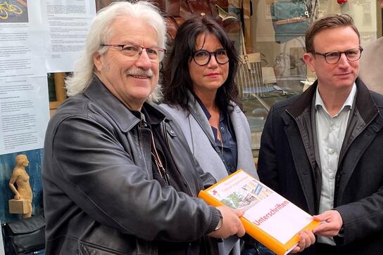 Peter Büscher (l.) und Carina Freytag-Hafen (M.) von der Bürgerinitiative „Liebe zur Augustenstraße“ übergeben 500 Unterschriften gegen die Umbaupläne an den CSU-Fraktionsvize Hans Theiss (r.).